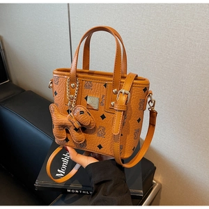 Close-up of orange bucket bag with bear print, metal nameplate and animal charm