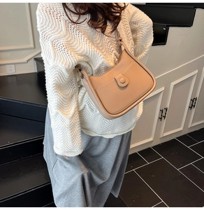 Detail of minimalist beige leather bucket bag with stitch accents on casual outfit