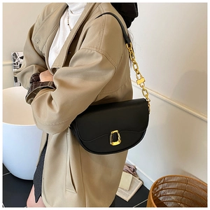 Detail of black leather saddle bag with vintage gold hardware buckle and chain strap