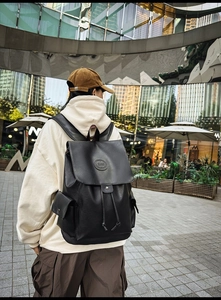 Outdoor side view of a black vintage PU leather backpack with drawstring closure