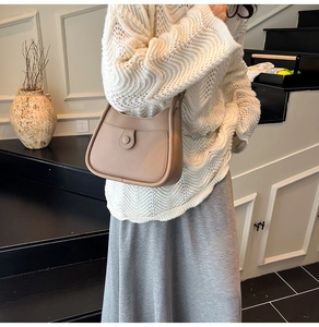 Detail of light brown lychee grain leather handbag with round buckle and front pocket