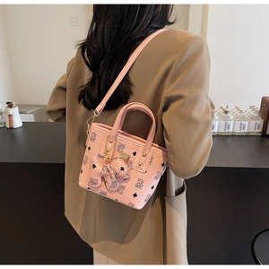 Detailed close-up of pink bucket bag with bear print pattern and cute 3D bear charm