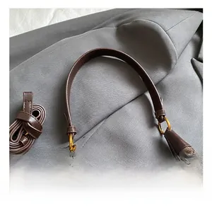 Détail du sac à main en daim et cuir avec anneaux dorés et poignée de transport confortable