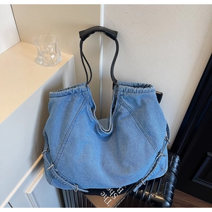 Dettaglio della borsa tote in denim azzurro con manici neri e chiusura a coulisse