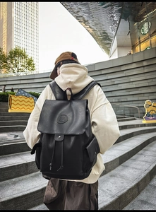 Street view of black leather vintage backpack featuring flap buckle and drawstring closure