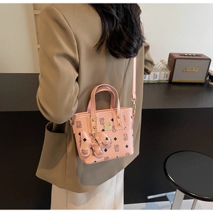 Detail view of pink bucket bag with diamond bear pattern and charm on model