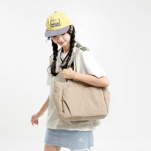 Detail of beige nylon tote bag with functional side pockets on model in studio