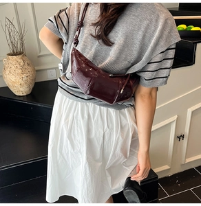 Detail view of burgundy glossy crescent moon bag with stitching and adjustable strap