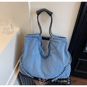 Macro della borsa tote in denim blu con cuciture a V su valigia nera