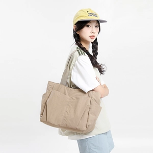 Detailed side view of khaki nylon tote bag with functional pockets and wide shoulder strap