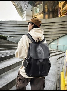 Detail view of a black vintage leather backpack with drawstring closure and embossed logo