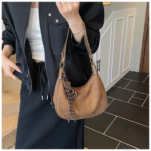 Détail d'un sac demi-lune en daim marron avec pendentif tressé et garnitures dorées