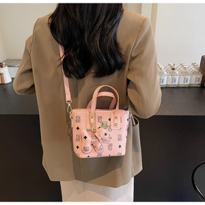 Detail of pink monogram bucket bag with plush dog charm and gold chain hardware