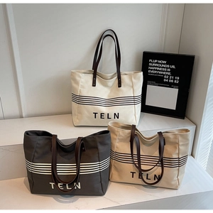 Detailed view of canvas tote bags with leather handles and striped base branding