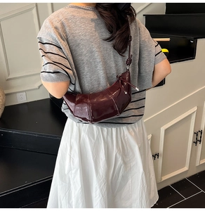 Detail of the high-gloss dark red patent leather croissant bag with fine stitching