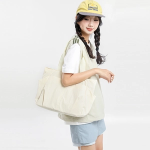 Side view of a large cream white tote bag with side pockets on a model for daily use