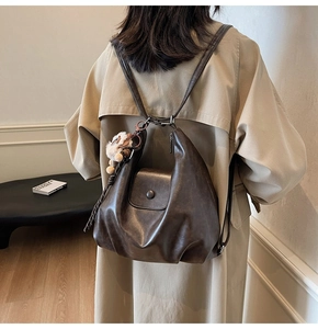 Detail of dark brown faux leather pleated backpack with cute plush cat charm on side