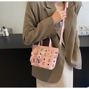 Detail of pink bucket bag featuring monogram pattern and a decorative bow charm