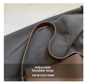 Close-up of adjustable strap and litchi texture on vintage brown leather bucket bag