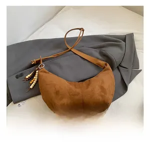 Detail der braunen Wildleder-Hobo-Tasche mit Vintage-Holzperlen auf grauem Blazer