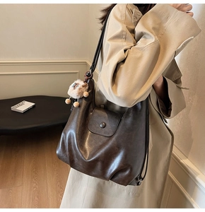 Detail of vintage brown leather tote bag with soft plush sheep charm and magnetic flap pocket