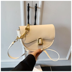 Detail of cream saddle bag with golden U-shaped clasp and thick chain decoration