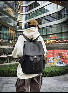 Close-up of black vintage leather backpack with drawstring closure and logo detail
