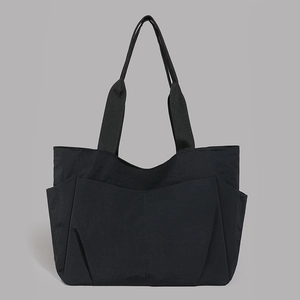 Detail of black nylon tote bag showing front layered pockets and side bottle holder
