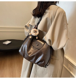 Detail of vintage brown PU leather tote with lion plush charm on khaki trench coat