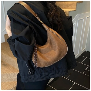 Gros plan du sac hobo en daim marron avec franges porté à l'épaule du mannequin