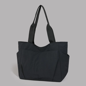 Detail view of large capacity black nylon tote bag with functional front and side pockets