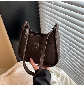 Detail of dark brown lychee leather bucket bag with a buckle flap and adjustable strap