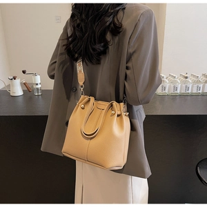 Detail of light brown bucket bag with wide bohemian woven strap and gold rivets