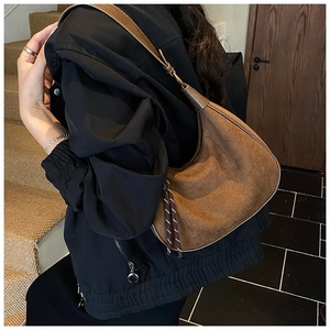 Détail du sac hobo marron mat avec pompon tressé et bandoulière en cuir lisse