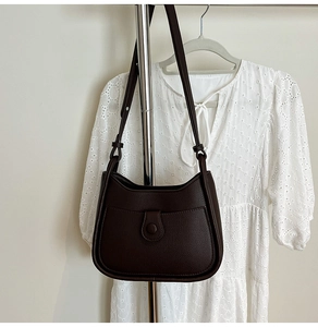 Detail of dark brown pebble leather crescent underarm bag with front pocket on a hanger