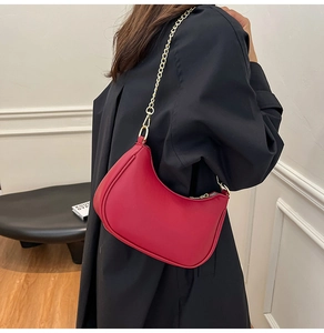 Close-up of a red leather hobo bag with a gold chain strap worn with a black coat