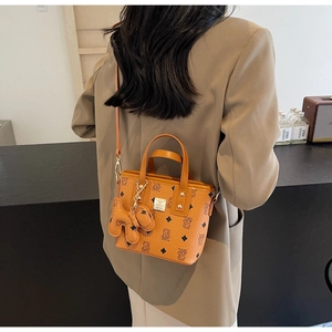 Detail shot of a brown monogram bucket bag with cute dog charm in an urban setting
