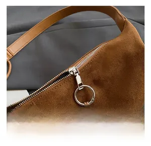 Details des silbernen Metallreißverschlusses und der Holzperlenquaste an brauner Wildledertasche