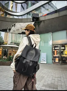 Detail of black synthetic leather backpack with drawstring closure and brand logo