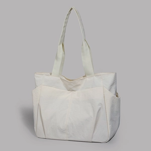Close-up of lightweight ivory tote bag showing geometric stitching and side pocket detail