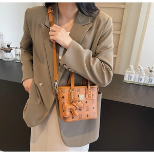 Detail of tan monogram bucket bag with removable strap and cute puppy pendant accessory