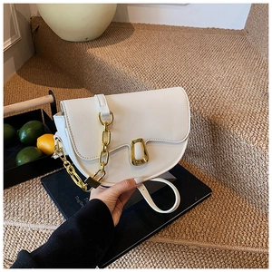 Detail of white saddle bag with gold chunky chain handle and fine stitching on stairs