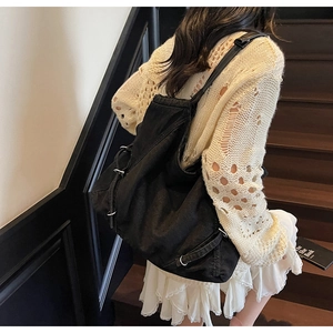 Dettaglio della borsa tote in denim nero con fibbie metalliche sulla scala in legno