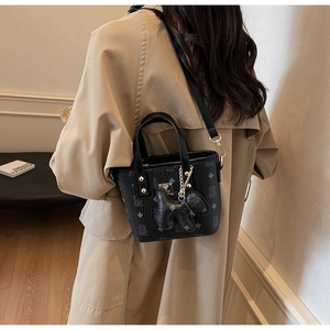 Detail of black monogram bucket bag with gold studs and a cute dog charm attachment