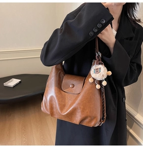 Detailed close-up of brown vintage leather tote with white sheep charm and metal closure