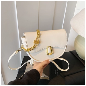 Detailed shot of white saddle bag with unique gold metal buckle and chunky chain link