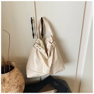 Detail view of beige large tote bag with pleated texture and stylish metal buckle accents
