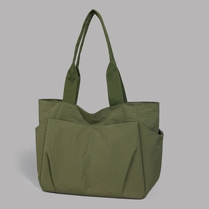 Detailed close-up of army green nylon tote bag with side pockets and durable webbing straps