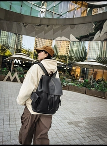Detailed view of black leather vintage backpack with drawstring and flap closure