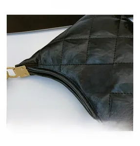 Detail of elegant black quilted leather bag featuring a premium gold metal turn-lock clasp